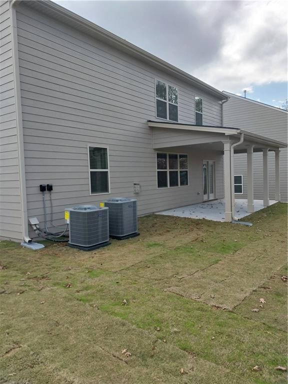 rear view of property with cooling unit, a yard, and a patio