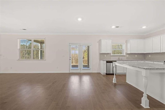 kitchen featuring white cabinetry, stainless steel dishwasher, light stone counters, and backsplash