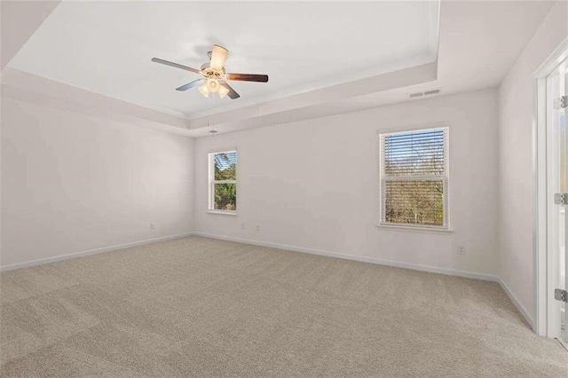 carpeted spare room featuring a raised ceiling and ceiling fan