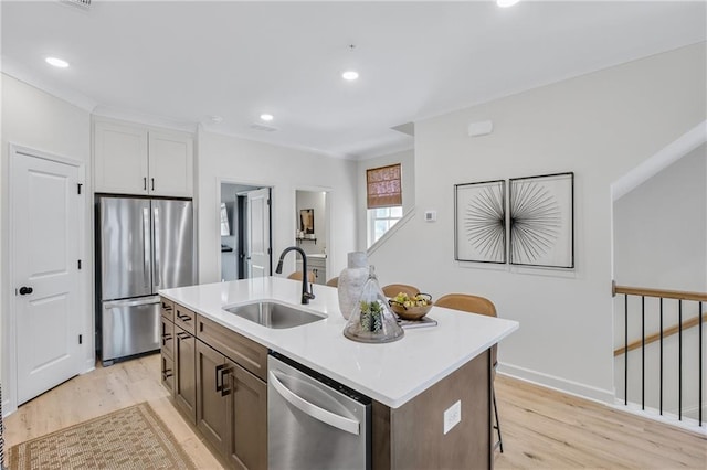 kitchen featuring a sink, light wood-type flooring, appliances with stainless steel finishes, and light countertops