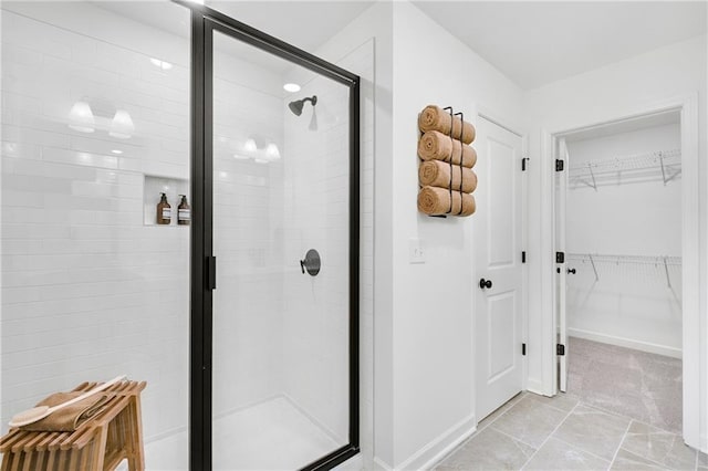 full bathroom featuring a walk in closet, baseboards, and a stall shower