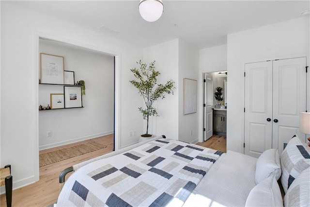 bedroom featuring light wood-style flooring, baseboards, and connected bathroom