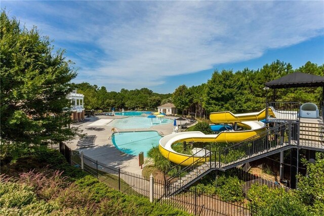 pool featuring a patio, a water slide, and fence