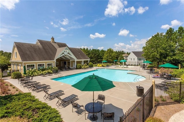 community pool with a patio and fence