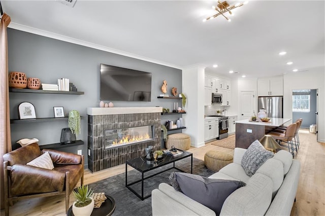 living room with baseboards, light wood-style flooring, recessed lighting, ornamental molding, and a tiled fireplace