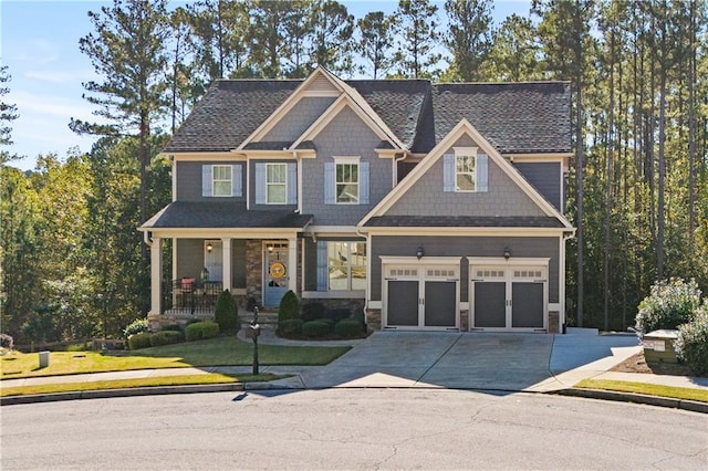 craftsman-style home featuring covered porch, a front yard, and a garage