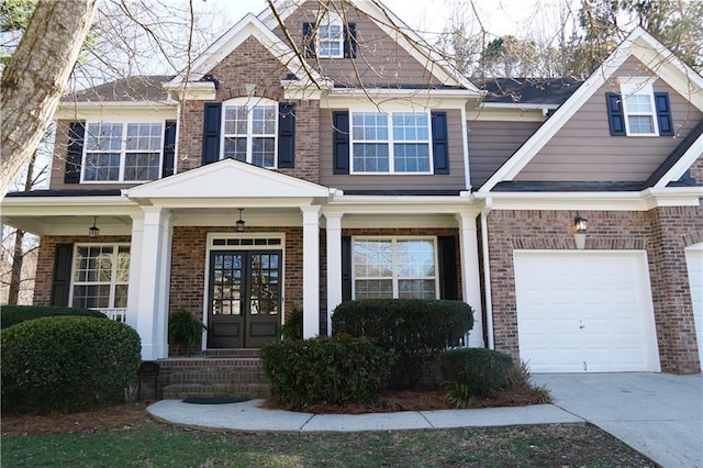 view of front of property with covered porch, french doors, brick siding, and driveway