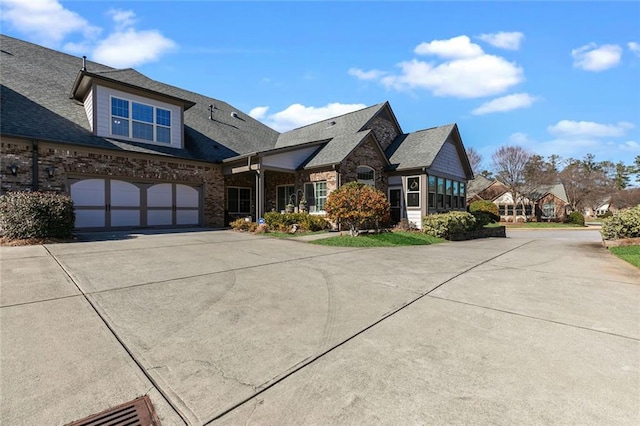 craftsman house with concrete driveway, brick siding, roof with shingles, and a garage