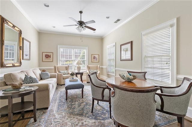 interior space featuring ornamental molding, a ceiling fan, wood finished floors, and visible vents
