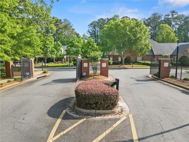 view of road with a gated entry, a gate, and curbs
