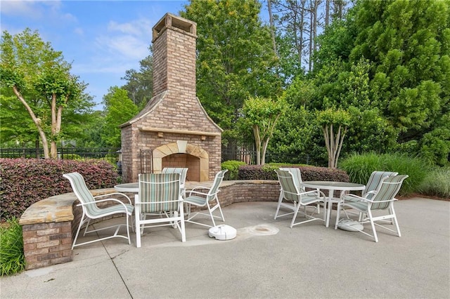 view of patio featuring fence, an outdoor brick fireplace, and outdoor dining space