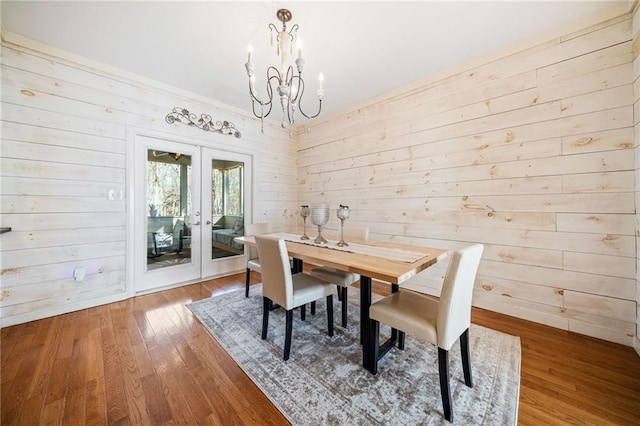 dining room with wood finished floors, french doors, baseboards, and a chandelier