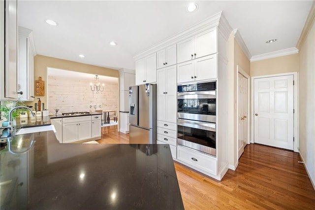 kitchen with dark countertops, appliances with stainless steel finishes, white cabinetry, and a sink