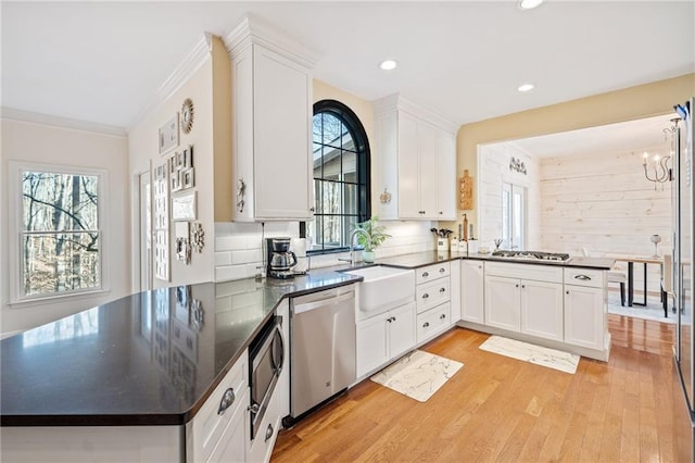 kitchen featuring dark countertops, a peninsula, stainless steel appliances, and a sink