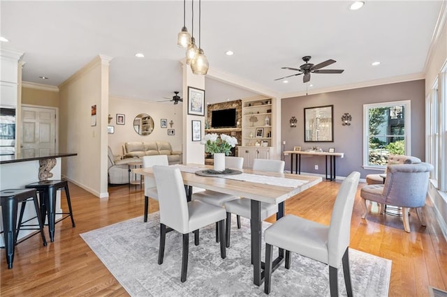 dining space with built in features, baseboards, light wood-style floors, and crown molding