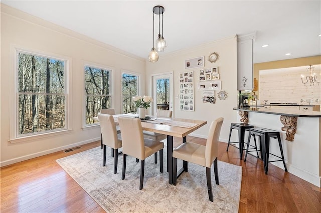 dining space with visible vents, ornamental molding, baseboards, and wood finished floors