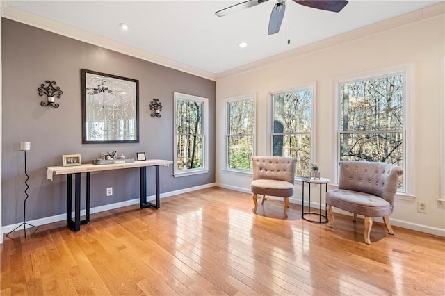 sitting room with ceiling fan, baseboards, light wood-style flooring, and ornamental molding