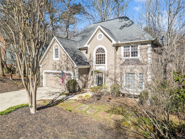 view of front facade with stucco siding, driveway, a shingled roof, and a garage