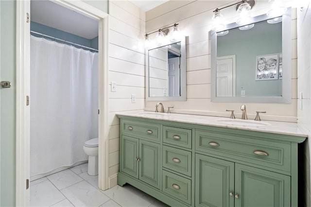 full bath featuring a sink, toilet, marble finish floor, and double vanity