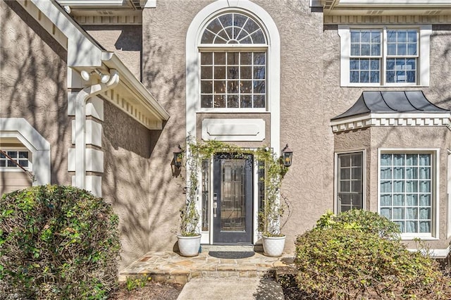 doorway to property with a standing seam roof, metal roof, and stucco siding