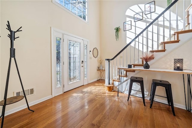 entrance foyer featuring visible vents, a high ceiling, baseboards, and hardwood / wood-style floors