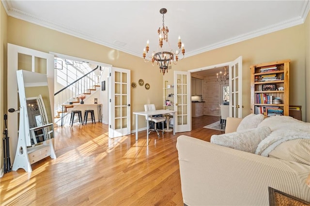 living room featuring a chandelier, light wood-style flooring, french doors, and stairs