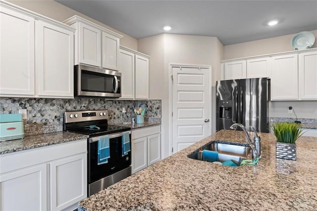 kitchen with backsplash, white cabinets, sink, appliances with stainless steel finishes, and stone countertops