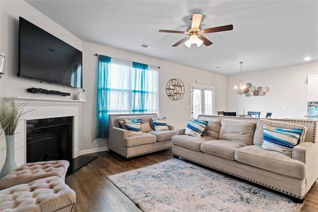 living room with dark wood-type flooring and ceiling fan with notable chandelier