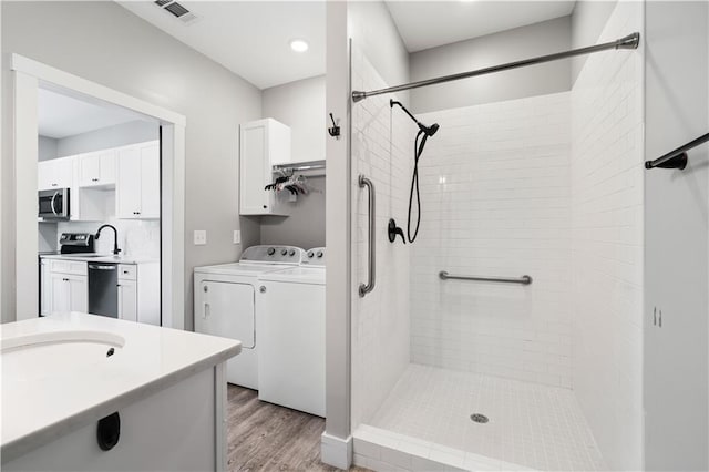 4286 Pool Rd, Winston, GA 30187 - bathroom with washing machine and clothes dryer, wood finished floors, a tile shower, and vanity