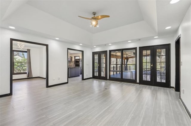 empty room with baseboards, a raised ceiling, wood finished floors, and french doors