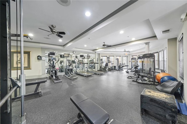 workout area featuring decorative columns, a raised ceiling, and ceiling fan