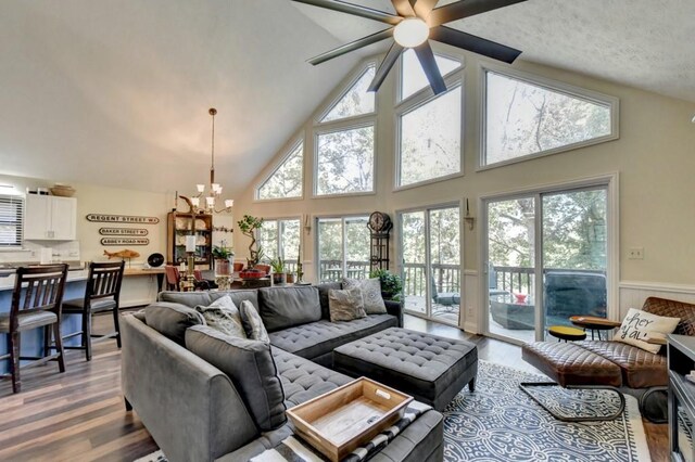 living room featuring hardwood / wood-style flooring, ceiling fan with notable chandelier, a healthy amount of sunlight, and high vaulted ceiling