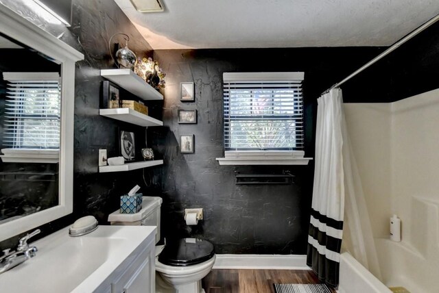 full bathroom featuring a wealth of natural light, wood-type flooring, shower / bath combo, and toilet