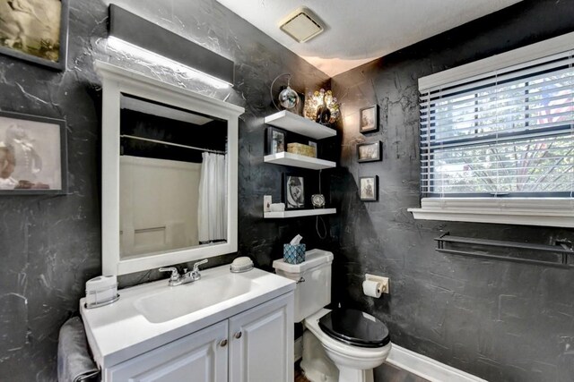 bathroom featuring curtained shower, vanity, and toilet