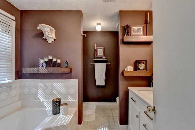 bathroom featuring tile patterned floors, a bathing tub, vanity, and a textured ceiling