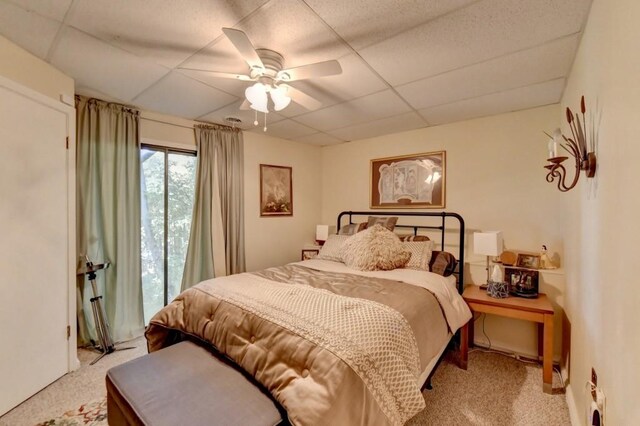 carpeted bedroom with a paneled ceiling and ceiling fan