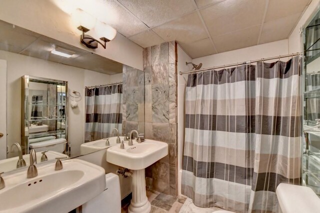 bathroom featuring a paneled ceiling and tile walls