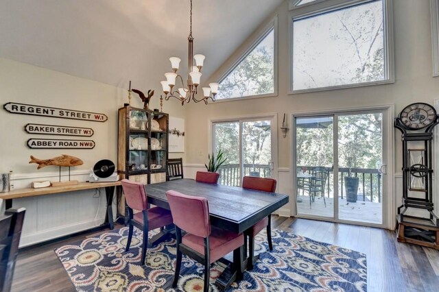 dining area featuring an inviting chandelier, high vaulted ceiling, and hardwood / wood-style flooring