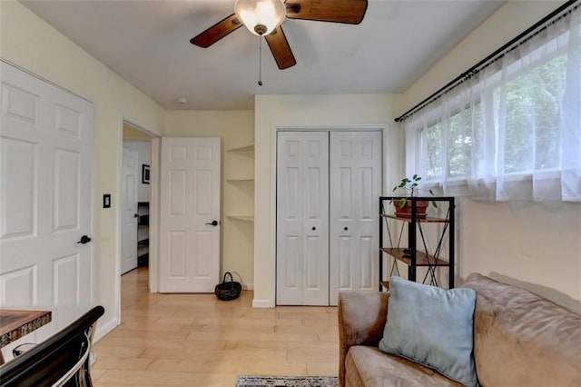 living area featuring a ceiling fan, baseboards, and light wood finished floors