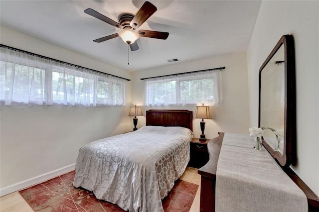 bedroom with baseboards, visible vents, multiple windows, and wood finished floors