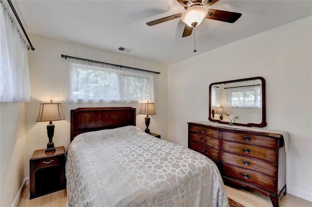 bedroom with baseboards, a ceiling fan, light wood finished floors, and visible vents