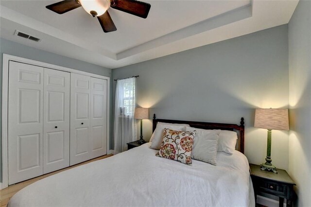 bedroom featuring a raised ceiling, ceiling fan, a closet, and visible vents