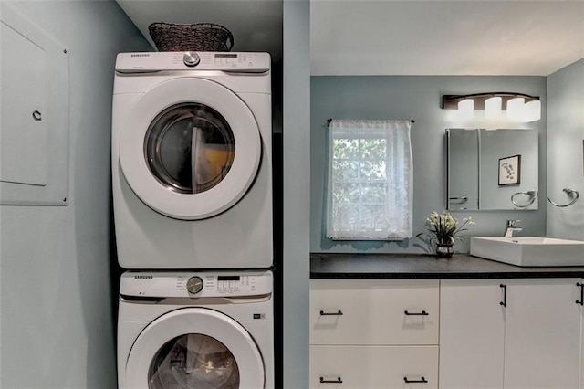 washroom featuring laundry area, a sink, and stacked washer / dryer