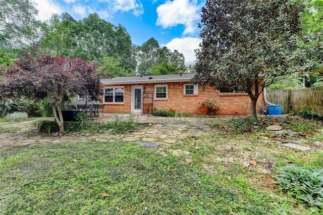 ranch-style house featuring brick siding, fence, and a patio area