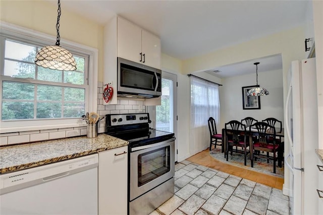 kitchen with light wood-type flooring, white cabinets, tasteful backsplash, appliances with stainless steel finishes, and decorative light fixtures