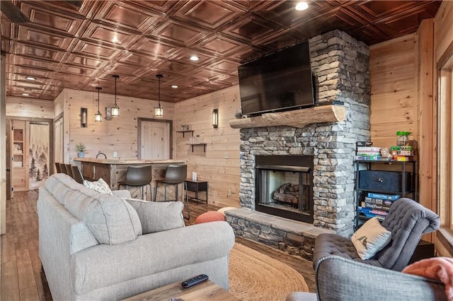 living area with an ornate ceiling, wooden walls, and wood finished floors