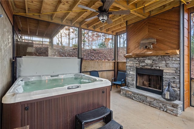 view of patio / terrace with an outdoor stone fireplace and a hot tub