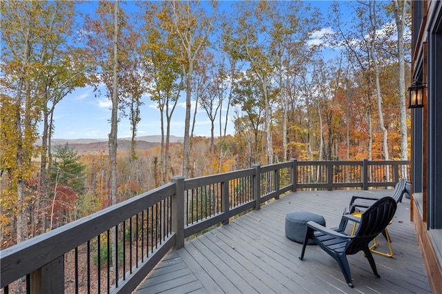 wooden deck featuring a wooded view and a mountain view