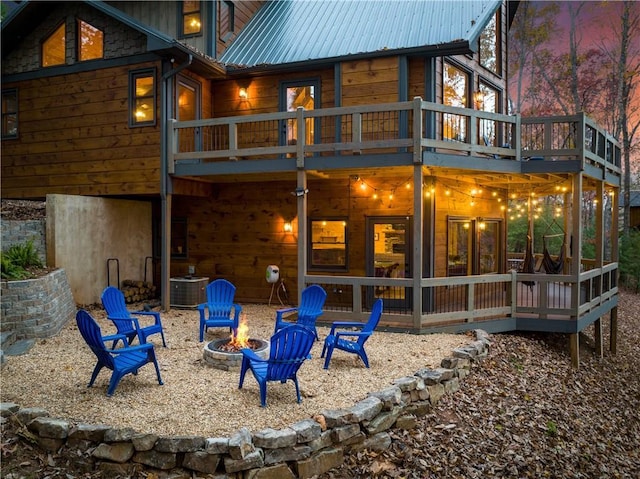 rear view of property with a patio, metal roof, a deck, cooling unit, and a fire pit