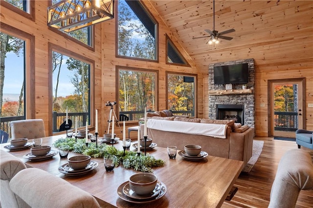 sunroom / solarium featuring a ceiling fan, lofted ceiling, wooden ceiling, and a stone fireplace